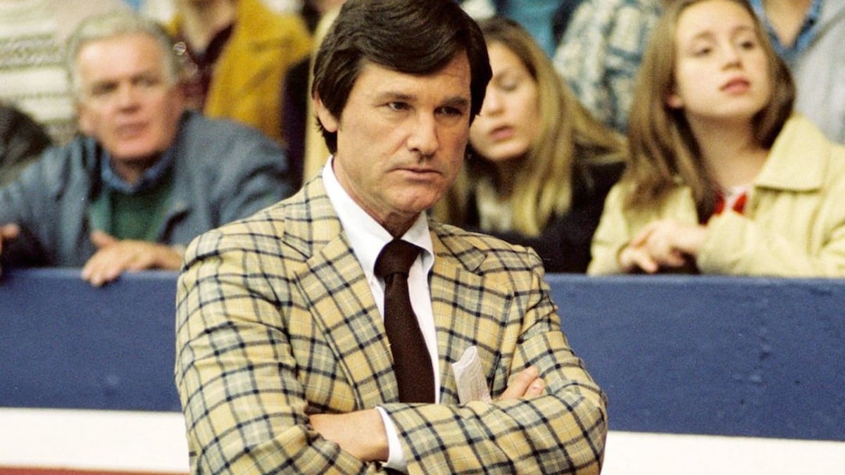 Kurt Russell with his arms crossed in a hockey rink
